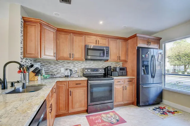 a kitchen with granite countertop a sink stainless steel appliances and cabinets