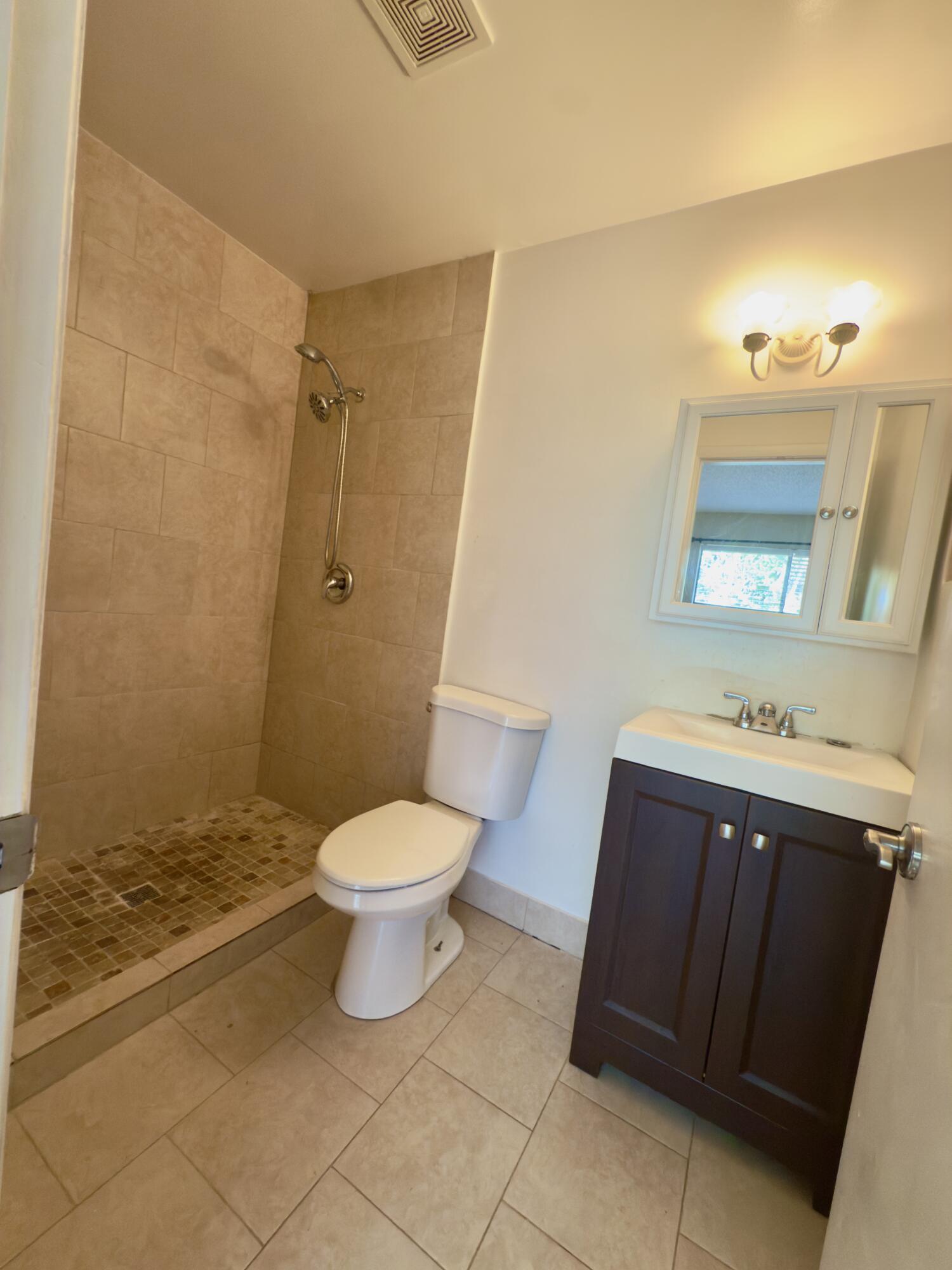 799 Hill Drive, Unit F West Palm Beach, FL 33415 - Photo 10 of 14 a bathroom with a sink a toilet and a mirror