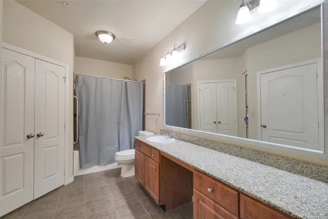 a spacious bathroom with a granite countertop sink and a mirror