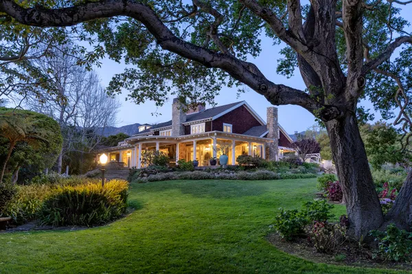 a front view of a house with a garden and trees