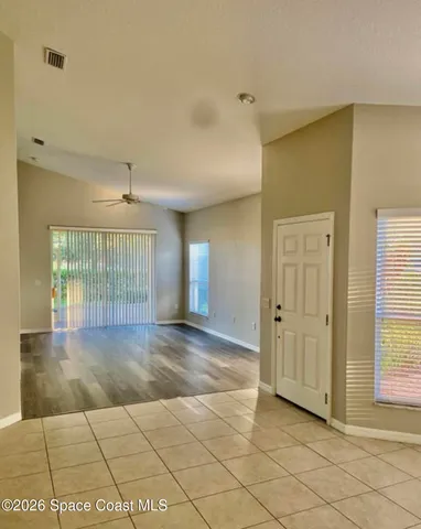 a view of empty room with wooden floor and fan