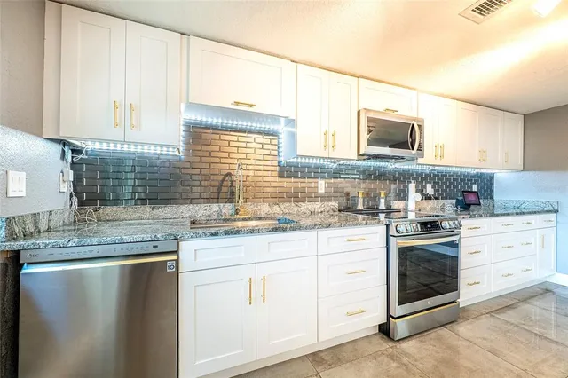 a kitchen with granite countertop white cabinets and white stainless steel appliances