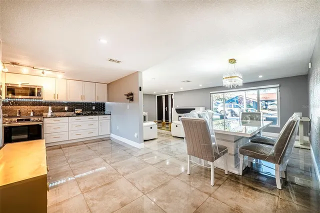 a kitchen with stainless steel appliances kitchen island granite countertop a stove a sink a dining table and chairs