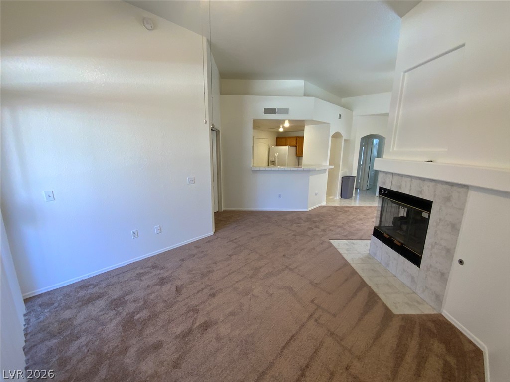7400 West Flamingo Road, Unit 1039 Las Vegas, NV 89147 - Photo 5 of 40 A spacious common area boasts soaring ceilings and a cozy fireplace, seamlessly connecting to an inviting kitchen.