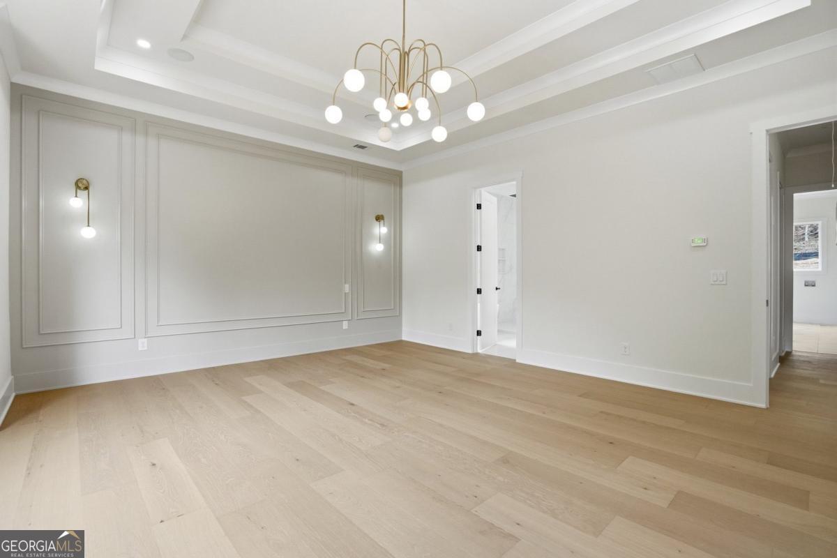 1557 Whitley Road Dacula, GA 30019 - Photo 17 of 46 en empty room with wooden floor and chandelier