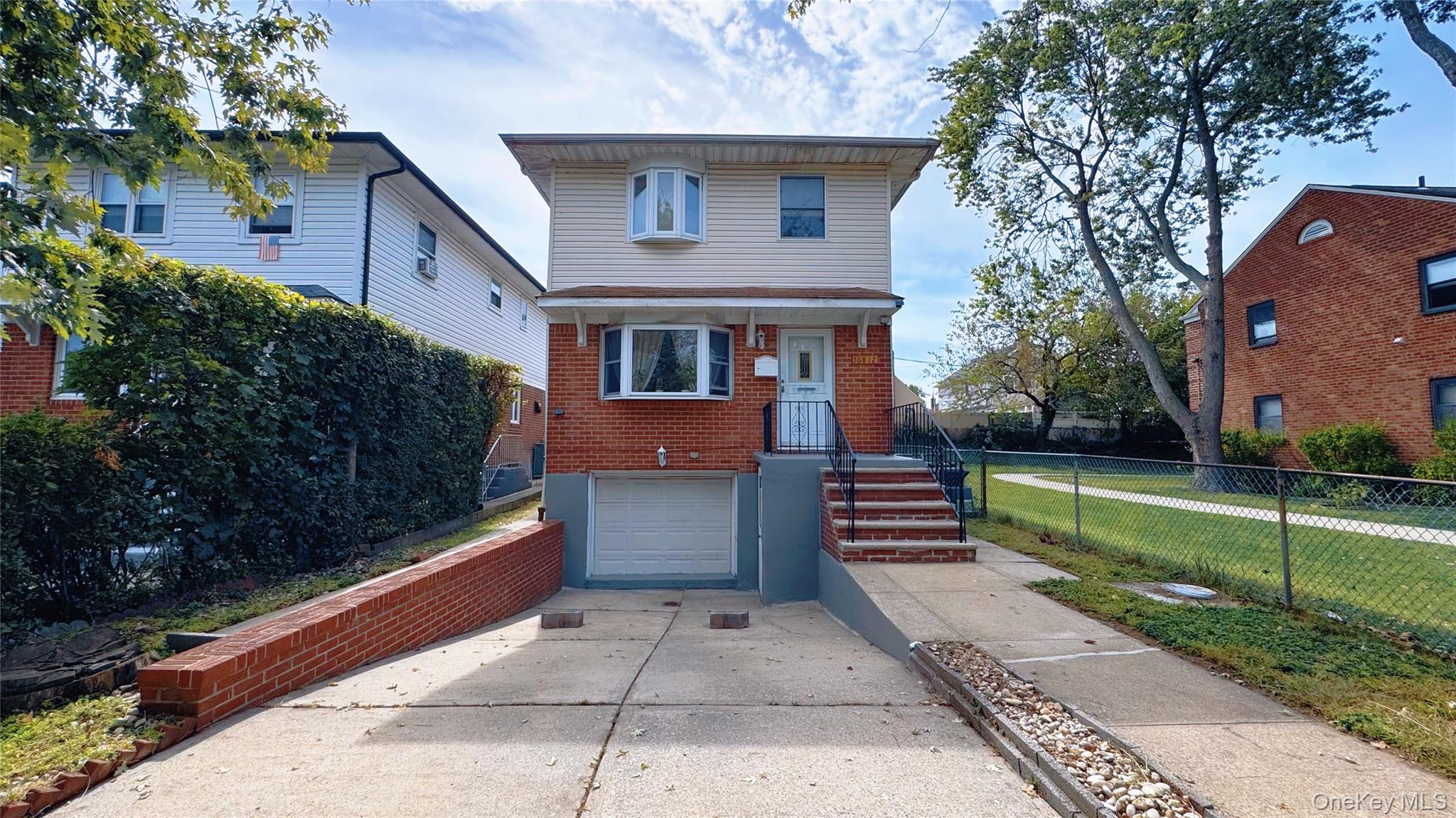 American foursquare style home with driveway, brick siding, and a garage
