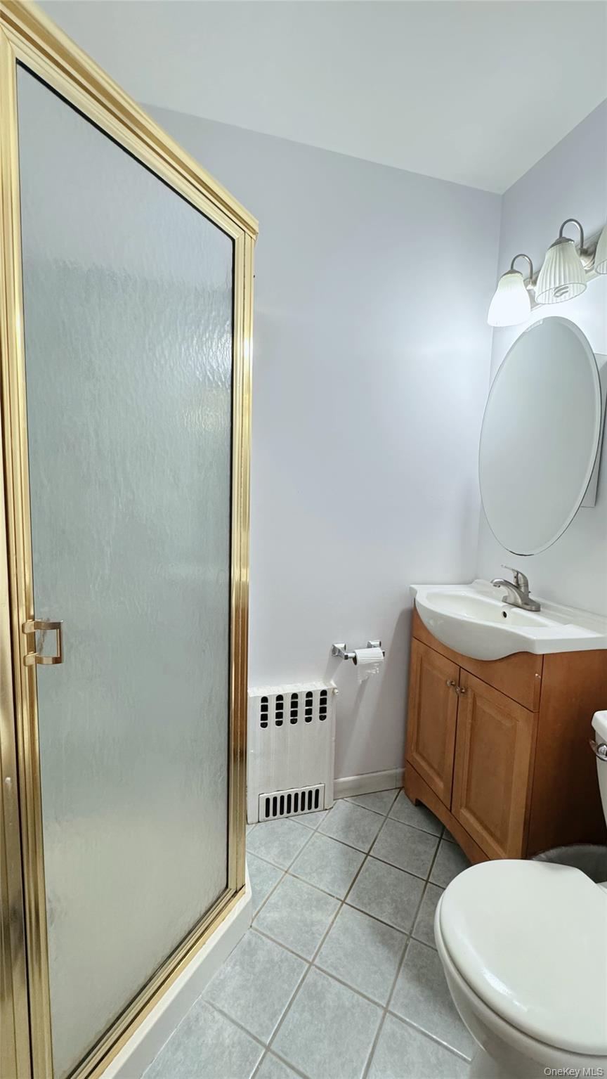 168-12 19th Avenue Queens, NY 11357 - Photo 20 of 27 Full bath featuring light tile patterned floors, vanity, a shower stall, and radiator