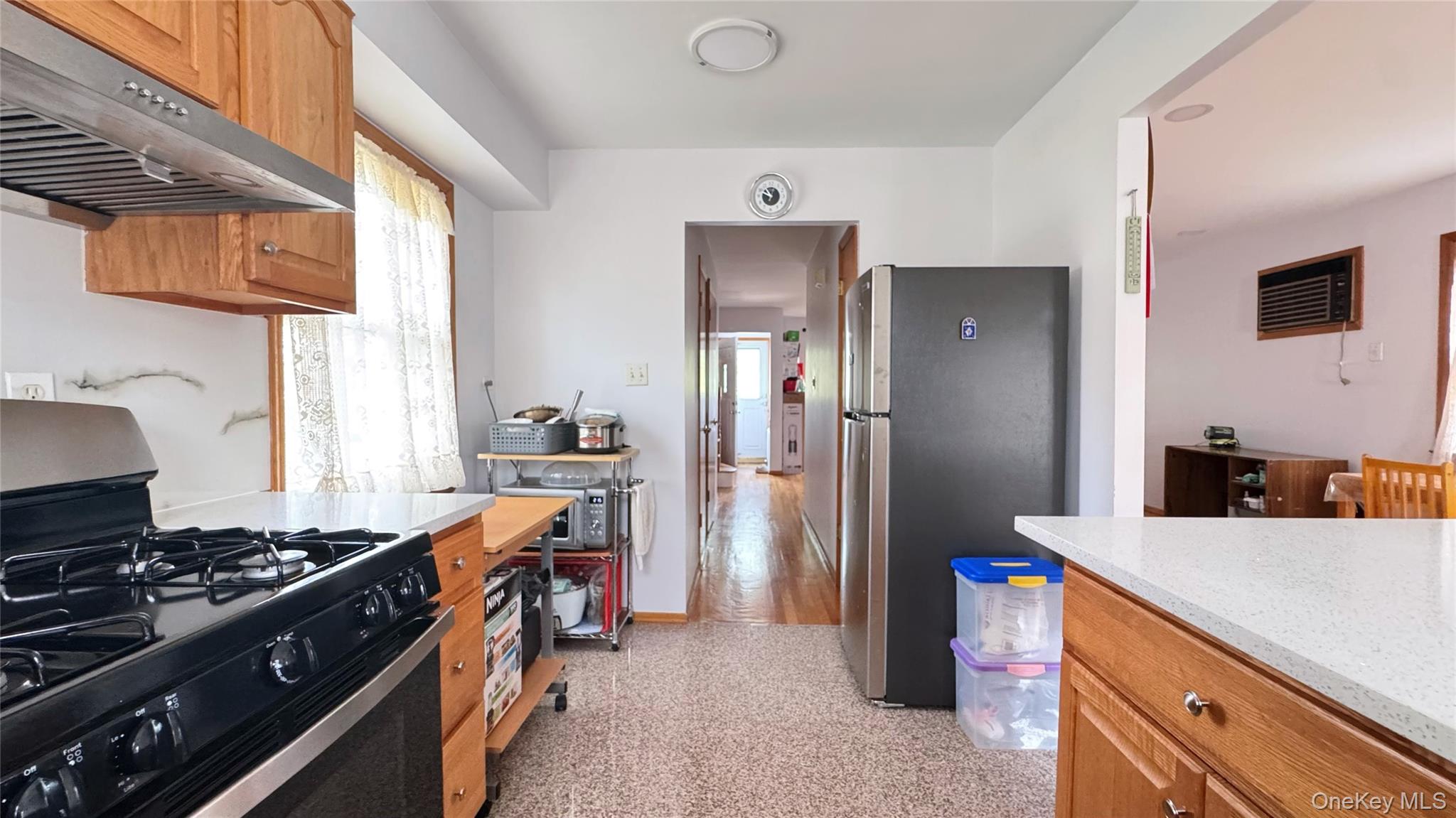 168-12 19th Avenue Queens, NY 11357 - Photo 10 of 27 Kitchen with appliances with stainless steel finishes, under cabinet range hood, brown cabinets, and light stone countertops