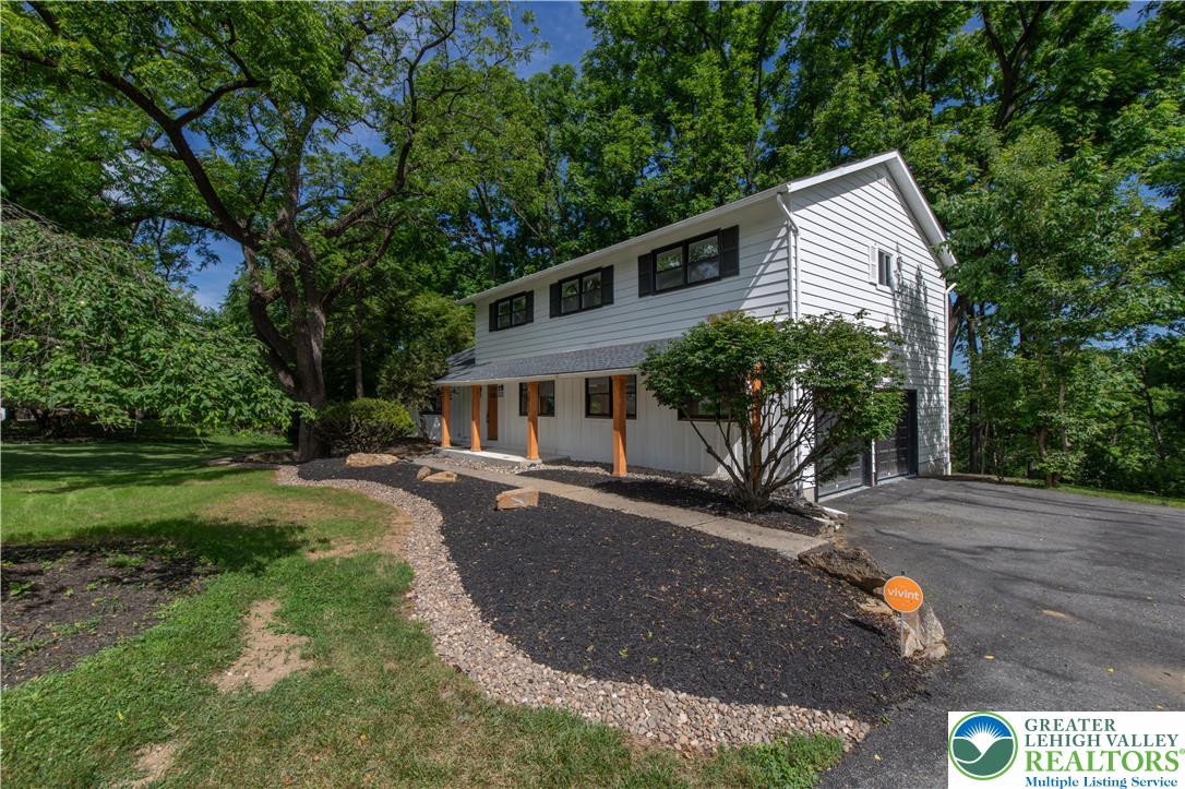 2011 Greenwood Road Allentown, PA 18103 - Photo 3 of 52 A well-maintained facade with striking white siding and contrasting dark shutters, framed by verdant trees and a paved driveway.