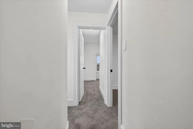 a view of a hallway with white wooden cabinets