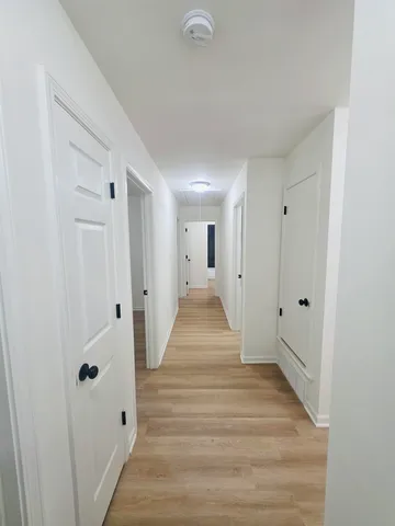 a view of a hallway with wooden floor and a bathroom