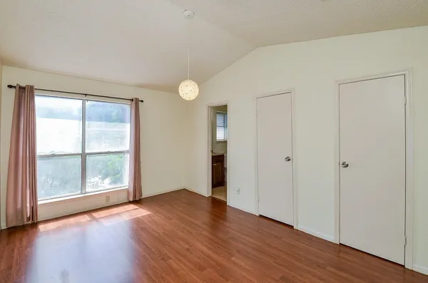 an empty room with wooden floor and windows