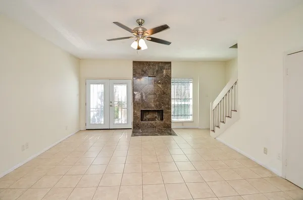 a view of an empty room with chandelier fan and fire place