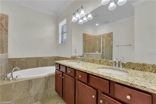 a bathroom with a granite countertop bathtub a sink and a mirror