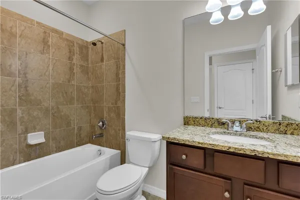 a bathroom with a granite countertop sink mirror toilet and bathtub