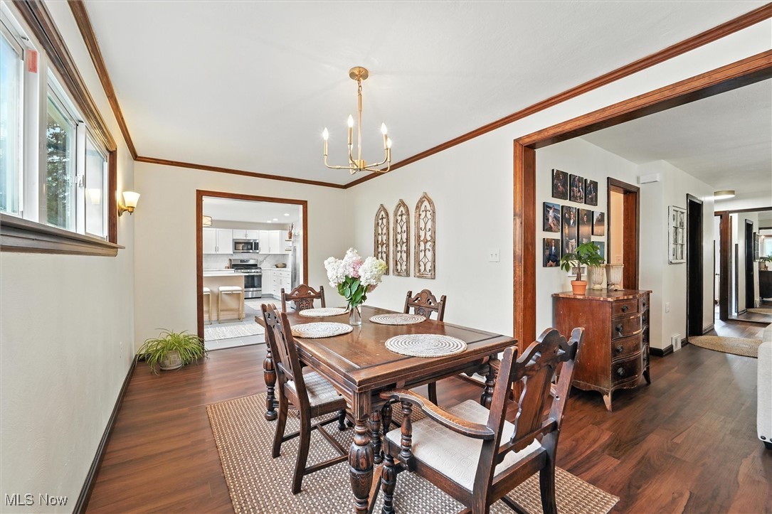 194 Ansel Road Geneva, OH 44041 - Photo 17 of 41 Dining space with dark wood-style flooring, a chandelier, and ornamental molding