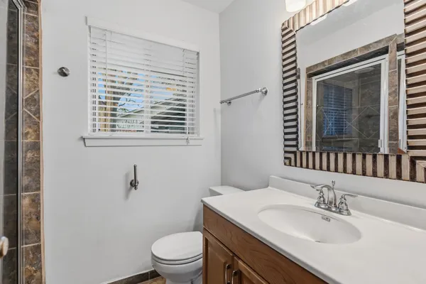 a bathroom with a granite countertop sink toilet a mirror and a window