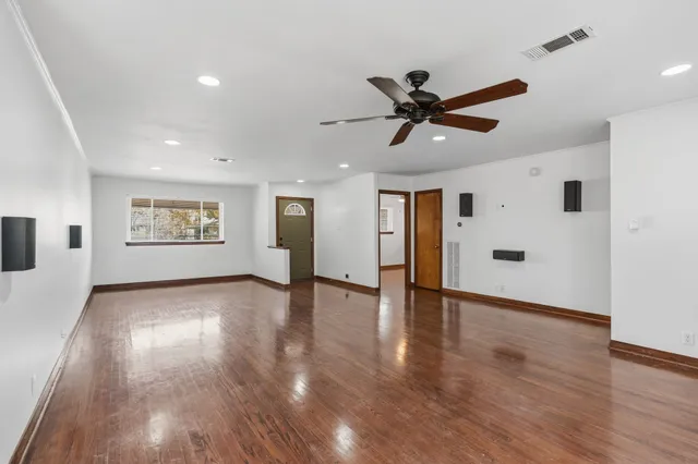 a view of an empty room with window and wooden floor
