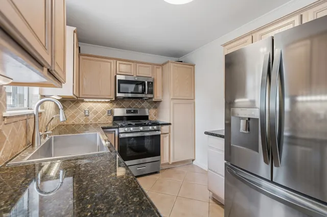 a kitchen with granite countertop a refrigerator and a stove top oven