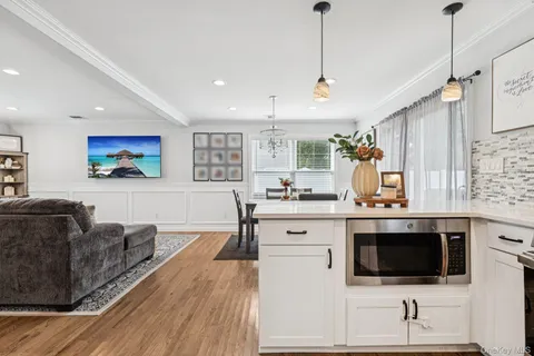 a view of living room kitchen with stainless steel appliances granite countertop a stove and a sink