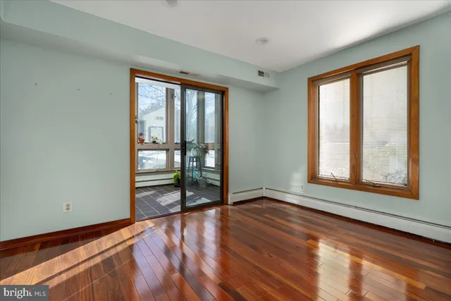a view of an empty room with window and wooden floor