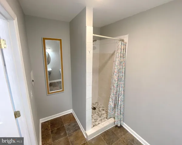 a view of an empty room with mirror and door