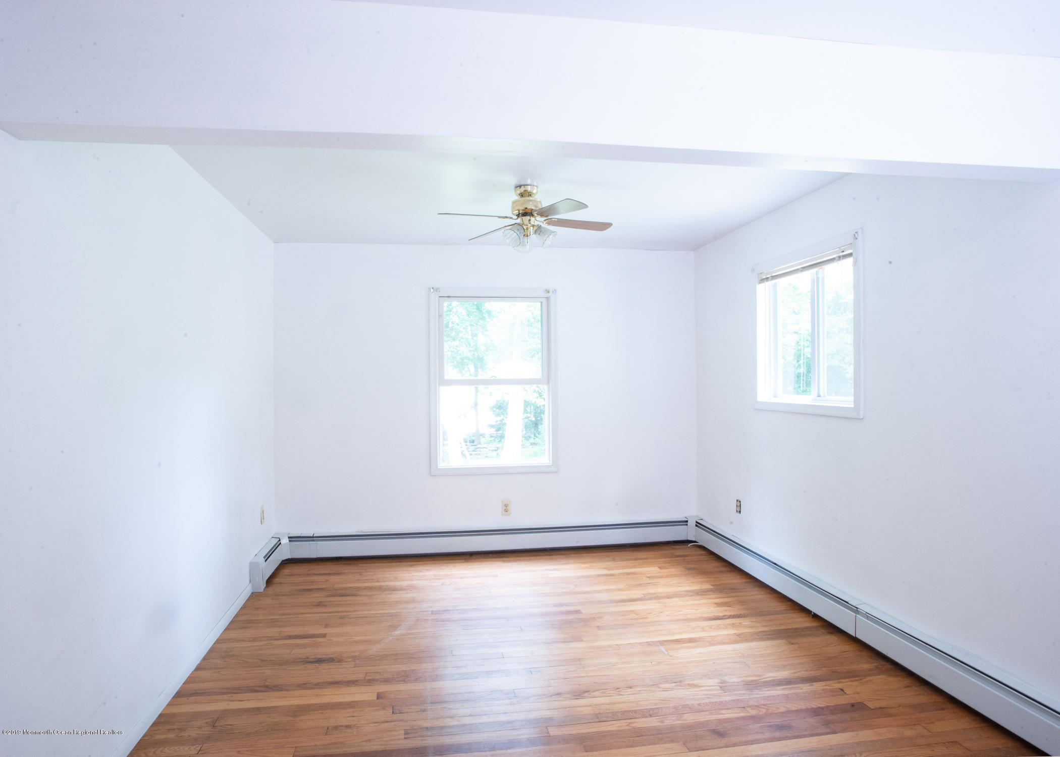 802 West Farms Road Howell, NJ 07731 - Photo 9 of 16 an empty room with wooden floor chandelier fan and windows
