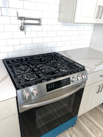 160 200 West Henefer, UT 84033 - Photo 6 of 25 Kitchen view of stainless steel range with gas stovetop, white cabinetry, pot filler, and light stone countertops