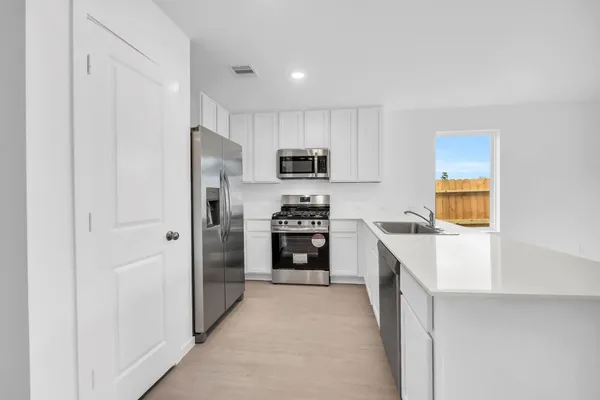a kitchen with granite countertop a refrigerator and a stove top oven