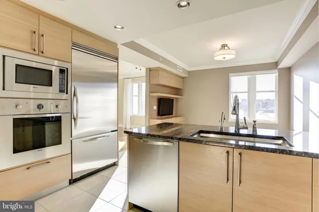 a kitchen with stainless steel appliances kitchen island granite countertop a refrigerator a stove and a sink