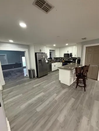 a large white kitchen with lots of counter space and stainless steel appliances