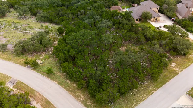 an aerial view of residential house with outdoor space and trees all around