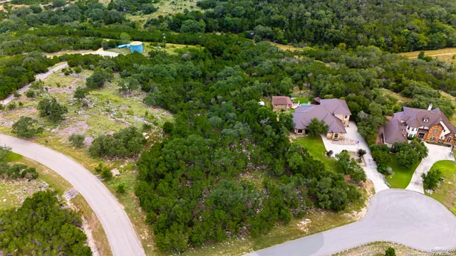 an aerial view of residential house with outdoor space and trees all around