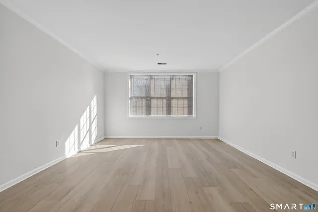 an empty room with wooden floor chandelier fan and windows