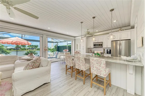 a living room with stainless steel appliances granite countertop furniture and a chandelier