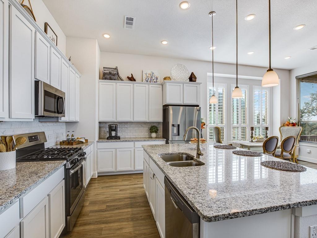 8409 Prairie Rye Drive Lago Vista, TX 78645 - Photo 4 of 17 a kitchen with stainless steel appliances granite countertop a sink a stove and a wooden floors