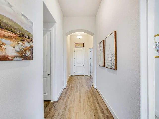 a view of a hallway with wooden floor and a bathroom