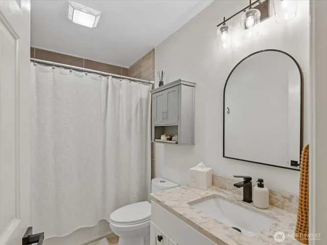 a bathroom with a granite countertop sink toilet and shower