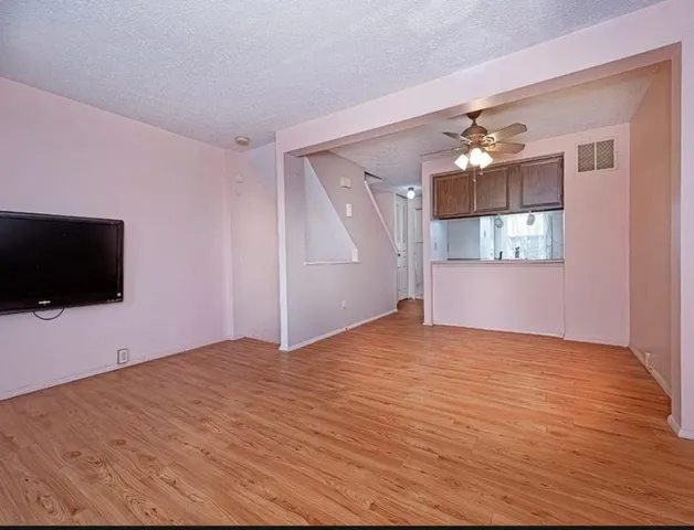 a view of empty room with wooden floor and fan