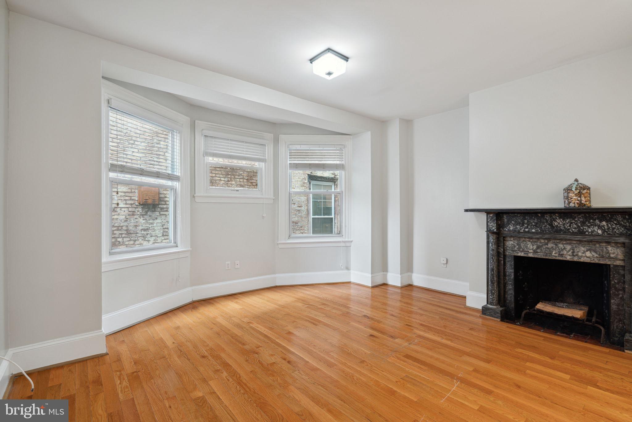 a view of empty room with wooden floor and fireplace