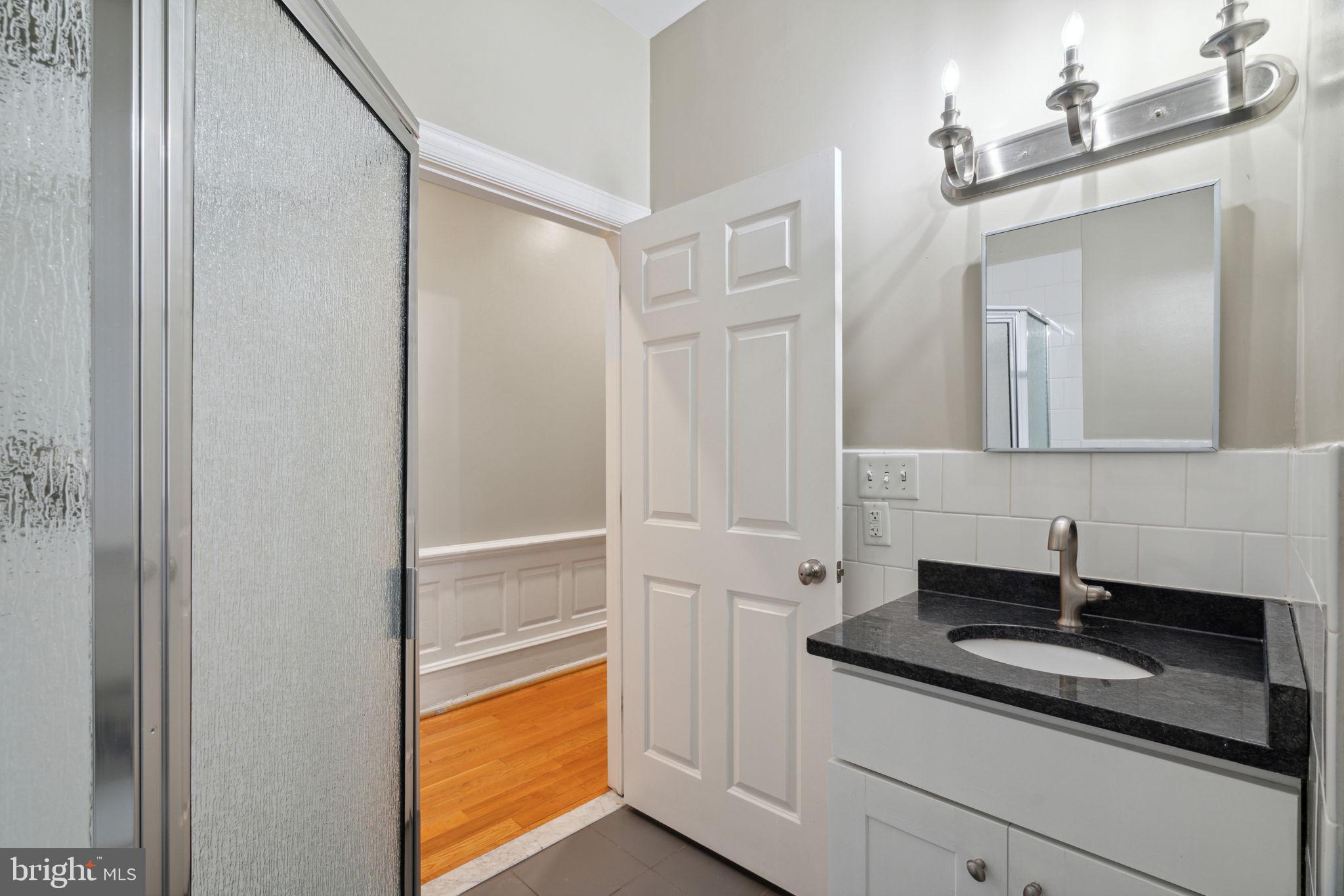 1955 Locust Street, Unit 2R Philadelphia, PA 19103 - Photo 13 of 19 a bathroom with a granite countertop sink and a mirror