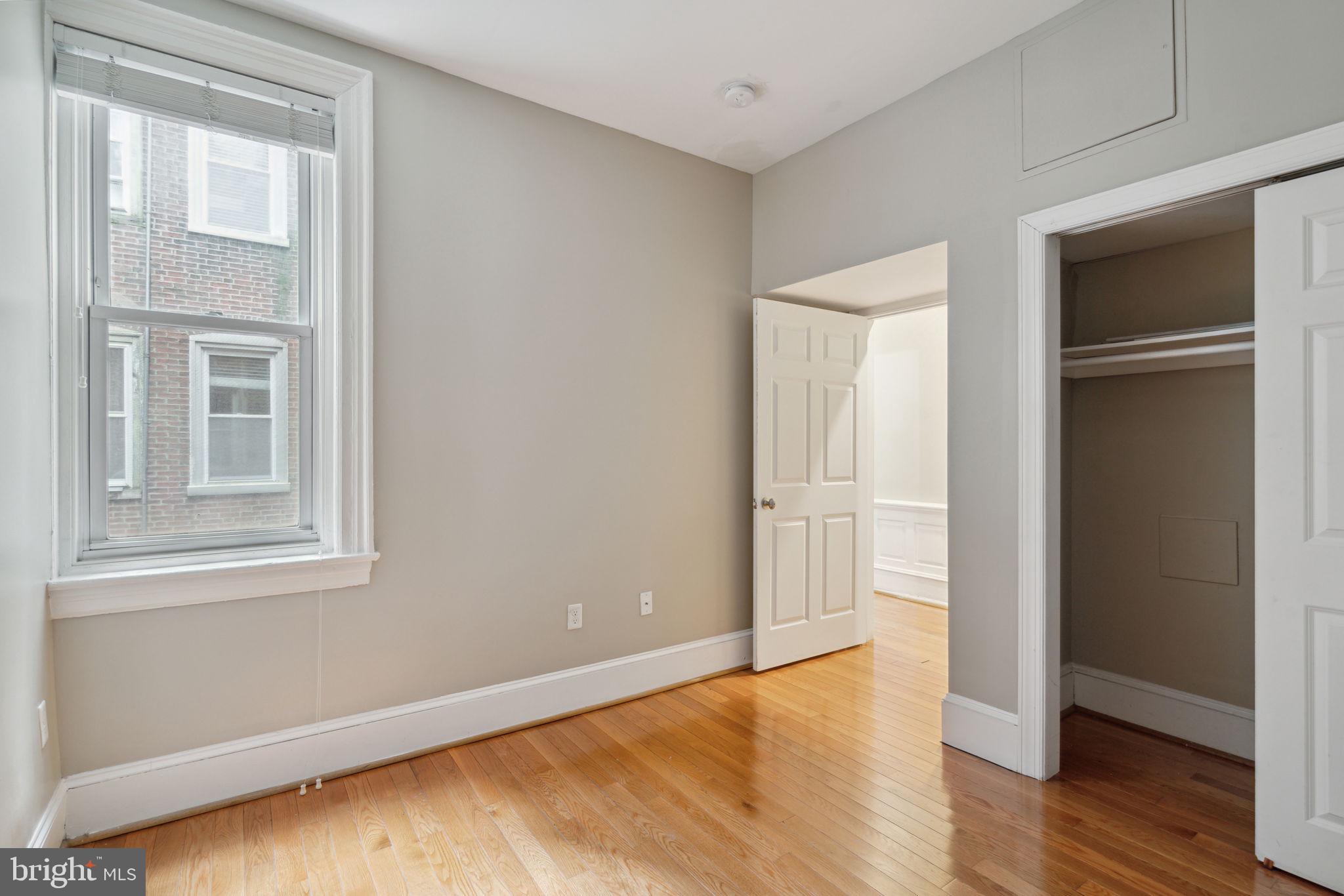1955 Locust Street, Unit 2R Philadelphia, PA 19103 - Photo 9 of 19 a view of an empty room with wooden floor and a window