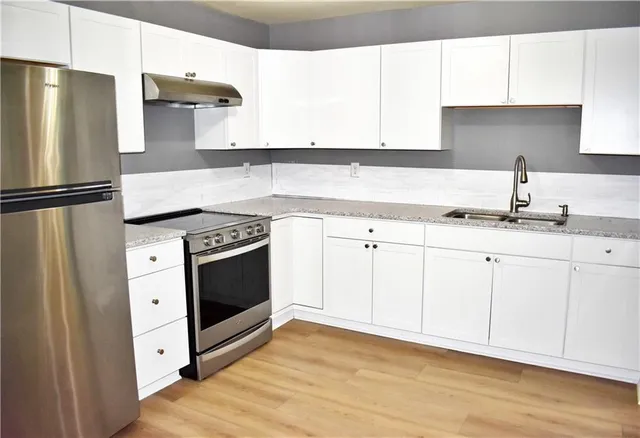a kitchen with stainless steel appliances granite countertop a refrigerator sink and white cabinets