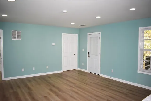an empty room with wooden floor and windows