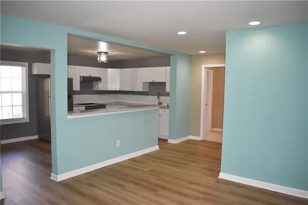 a room with kitchen island a sink wooden floor and a refrigerator