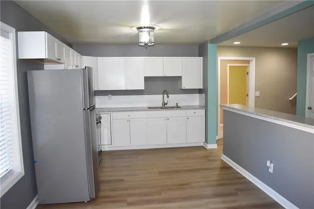 a kitchen with a refrigerator a sink and dishwasher with wooden floor