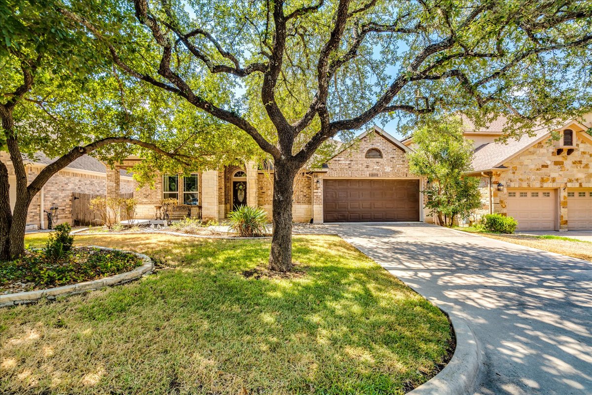12909 Medina River Way Austin, TX 78732 - Photo 2 of 36 Mature oak trees shade the stone and brick facade of this welcoming suburban home.