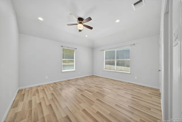 a view of empty room with wooden floor and fan