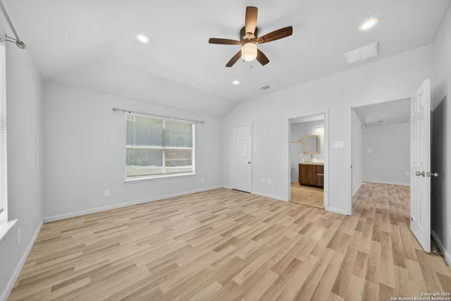 a view of empty room with wooden floor and ceiling fan