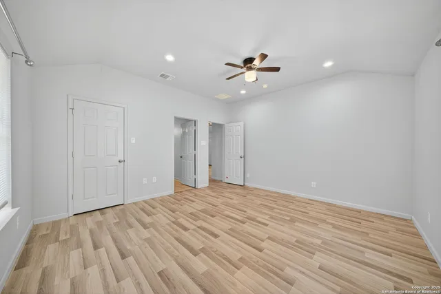 a view of empty room with wooden floor and fan